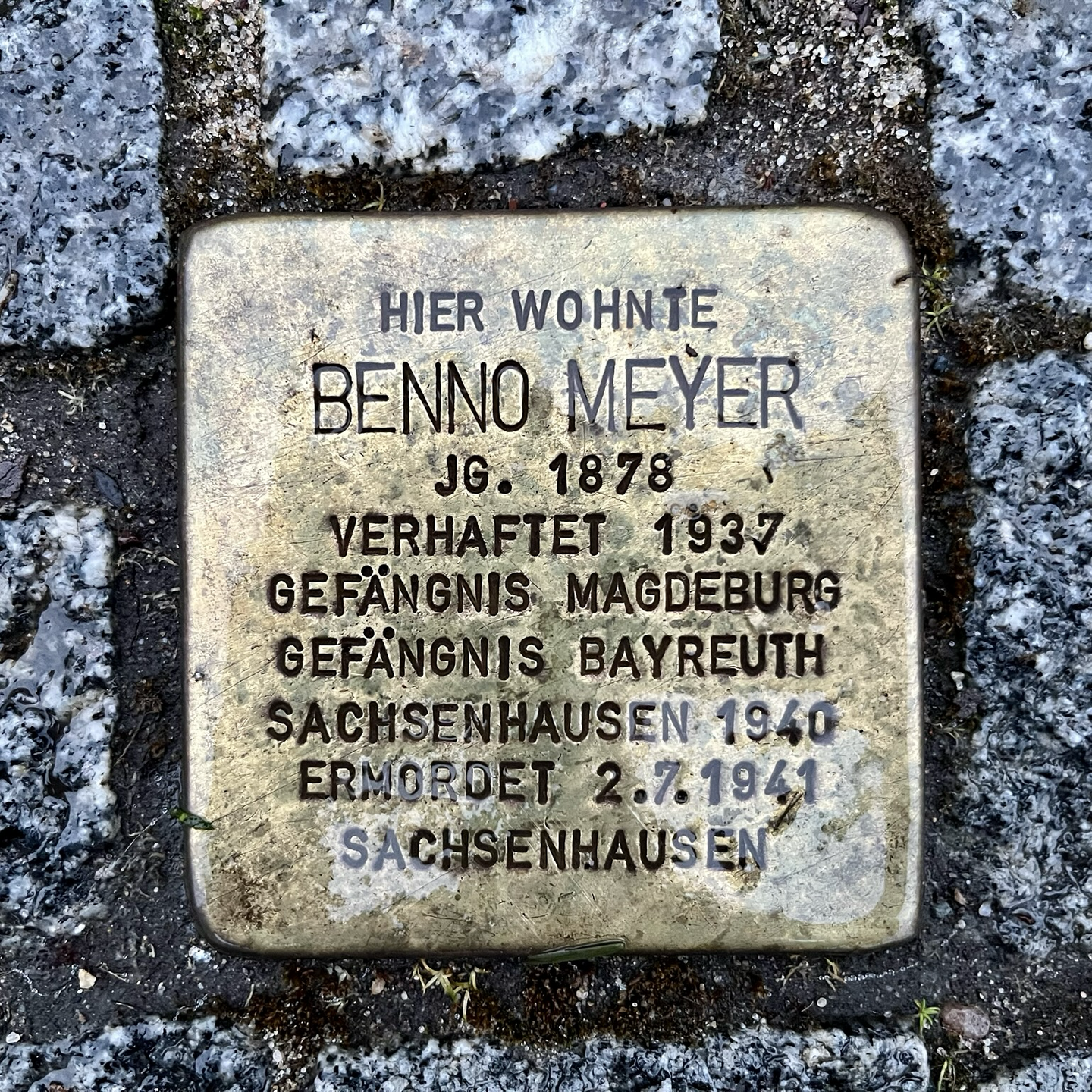 Foto einer in den Gehweg eingelassenen quadratischen Messingplatte mit der Inschrift:  Hier wohnte Benno Meyer. Jg. 1878. Verhaftet 1937. Gefängnis Magdeburg. Gefängnis Bayreuth. Sachsenhausen 1940. Ermordet 2.7.1941. Sachsenhausen.